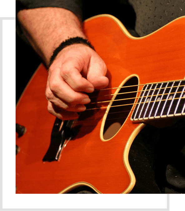 A person playing an orange guitar with their hand on the string.