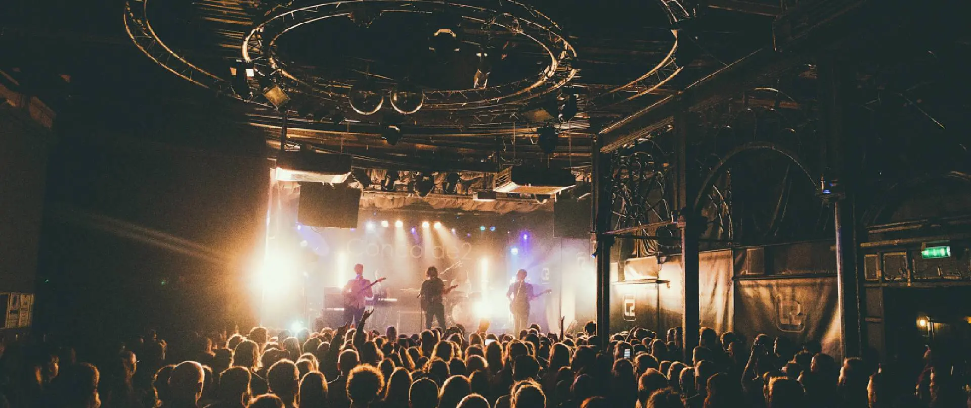 A crowd of people in front of stage lights.