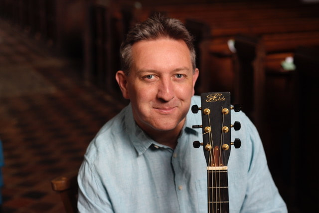 A man with a guitar in front of him.