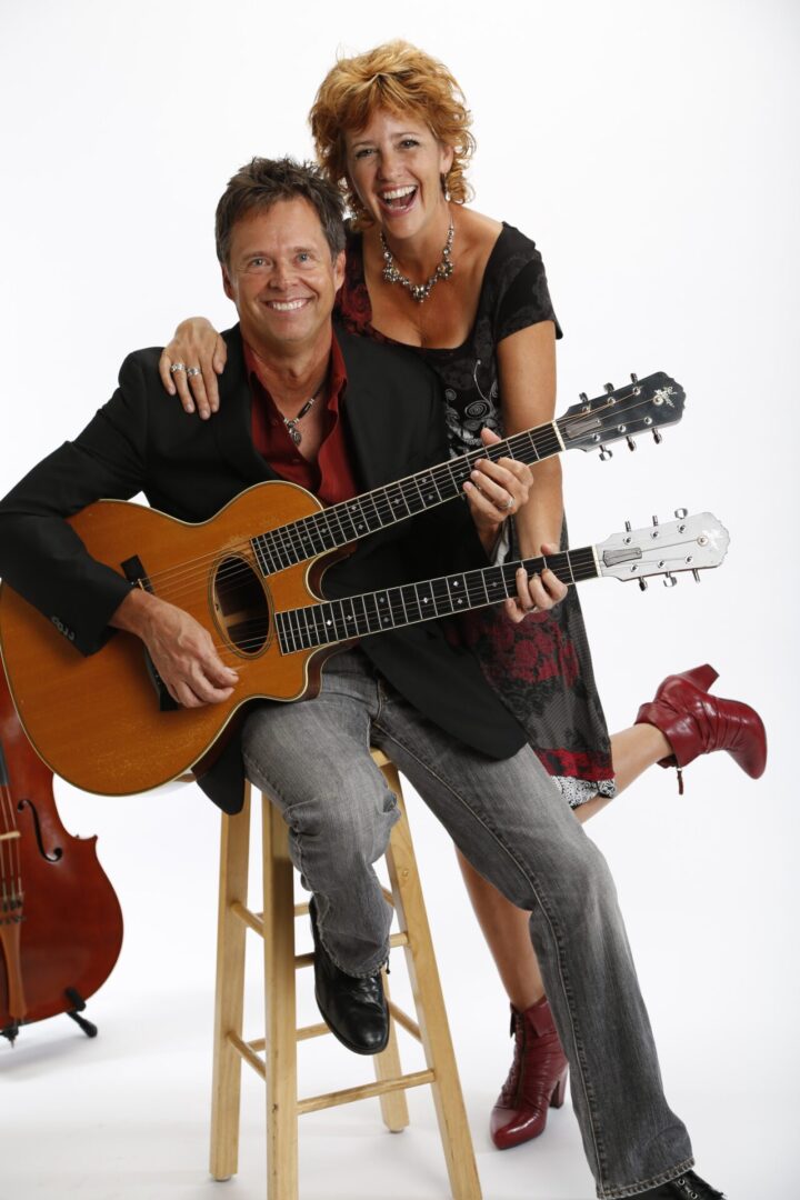 A man and woman holding guitars posing for the camera.
